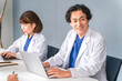 © buritora - Doctors, both male and female, in white coats, sitting at their desks and working.