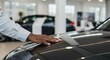 © Bakha - Car hood hand touching car dealership interior modern salesroom