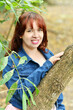 © Cristyan - Mujer joven guatemalteca recostada sobre un tronco de árbol de paseo por un área verde, espacio natural al aire libre.