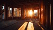 © khopidd232 - Sunlight streams through wooden wall studs of a residential house under construction during golden hour