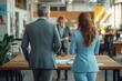 © Monika - two professionals in suits stand at a wooden conference table facing a colleague in a modern open-plan office, focused and serious during a meeting