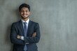 © Visual Odyssey - Young professional man in a suit standing confidently against a gray background wall