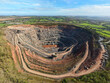 © AmazingAerialAgency - Aerial view of Old Cliffe Hill quarry showing the deep terraced excavation pit and surrounding green countryside under a blue sky in Stanton under Bardon, England, United Kingdom.