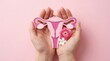 © Masque - Woman holding a uterus model and pink flowers for female reproductive system health concept.