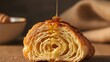 © Pemburu - Honey pouring over sliced buttery croissant on wooden table