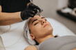 © qunica.com - Young woman receiving a professional facial treatment lying on a spa bed. Esthetician in gloves applies a cosmetic spray device over the face in a beauty center setting.