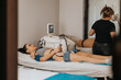 © qunica.com - A young woman lies on a treatment bed receiving a noninvasive body contouring procedure in a beauty center. A technician operates the device while another client is treated in the background.