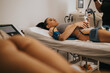 © qunica.com - A woman lies on a treatment bed receiving noninvasive body contouring on her abdomen at a beauty center.