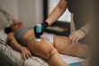 © qunica.com - A therapist performs a non-invasive body treatment on a woman's thigh using a handheld device. The client relaxes on a treatment bed during a spa procedure at a beauty center.