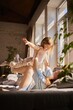 © Lustre Art Group  - Mother playing airplane game lifting daughter on legs in sunny living room. Concept of family lifestyle promotion, parenting services, emotional wellbeing and joyful childhood moments.