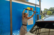 © bernardbodo - Mature woman smiling enjoying pressure washing her car