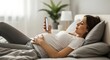 © Mustakim - Pregnant woman relaxing on bed with phone.