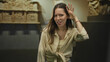 © Krakenimages.com - Woman with hand to ear listening in a museum gallery building beside a sculpture exhibit, attentive pose; curiosity discovery.