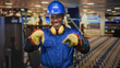 © Krakenimages.com - Man construction worker points both index fingers wearing blue hardhat yellow earmuffs and work gloves in studio; confidence safety readiness.