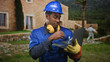 © Krakenimages.com - Man construction worker in hardhat typing on laptop with gloved hand at building exterior, yellow earmuffs around neck and wrench visible; diligence safety.