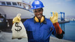 © Krakenimages.com - Man in hardhat holds money bag and makes ok sign at harbor dock while smiling, construction worker; confidence success.