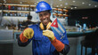 © Krakenimages.com - Man pointing finger and holding cuban flag, wearing blue hardhat, yellow gloves and ear protectors inside building bar; pride solidarity.