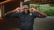 © Krakenimages.com - African american man police officer plugging ears with fingers, eyes closed and mouth open, badge and radio visible, under a covered wooden walkway on a street; frustration.