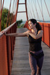 © FotoAndalucia - Woman Stretching and Warming Up Before Running on Red Bridge
