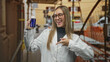 © Krakenimages.com - Woman holding blue bottle and smiling while wearing a lab coat in a narrow street with scaffolding; confidence wellness.