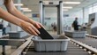 © olga_demina - Airport security checkpoint with a person's hands placing a phone in a bin on a conveyor belt