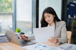 © maeching - Accountant woman working on financial investment on calculator, calculation, business growth analysis and marketing on graph at office.