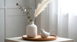 © Thai - Minimalist contemporary home interior decoration featuring an elegant ceramic vase with organic botanical elements and decorative accessories on a clean shelf against a neutral background.