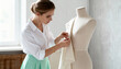 © Anna - A focused fashion designer pinning fabric onto a dress form in a bright studio. A professional dressmaker creating a custom garment. The process of clothing creation and tailoring