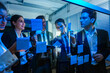 © ultramansk - Diverse cyber security team mapping out a secure network defense strategy on a glass wall in a high tech corporate office at night.