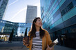 © Westend61 - Smiling businesswoman holding coffee and laptop in modern city
