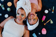 © oneinchpunch - Two happy women lying down, enjoying beauty treatment with under eye patches