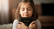 © tae - Peaceful young girl embracing Holy Bible book with closed eyes while praying, innocent child holding sacred scripture with devotion and faith in a spiritual religious moment.