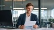 © 69 - Confident Businessman with Short Brown Hair Reviewing Documents in Modern Office Environment