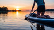 © Laura - Person kneeling on a paddleboard on a tranquil lake at sunset, enjoying a peaceful evening on the water.