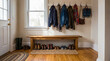 © Mary - Cozy and organized home entryway with a wooden bench, coat rack, and various shoes, boots, and personal accessories.
