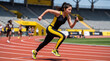 © pitchsinee - Focused female athlete sprinting on red track during relay race with competitors behind her