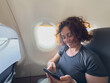 © Юлия Завалишина - Passenger woman is flying in plane. Girl using phone sitting by airplane window. Traveling female with smartphone inside plane enjoying flight. Woman using wifi connection on board. Traveling girl