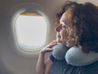 © Юлия Завалишина - Rest on plane. Young woman napping sitting by porthole in business jet using neck pillow for travel. Passenger girl flying in plane. Girl sleeping in airplane going on trip vacation. Traveling girl