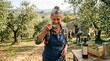 © Igor - Elderly caucasian female enjoying coffee in olive grove with harvesters in background