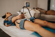 © qunica.com - A woman lies on a treatment bed receiving a noninvasive body contouring procedure at a beauty center. The scene shows a cosmetic slimming treatment using a handheld device on the abdomen.