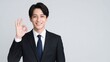 © YT - グレー背景でOKサインを見せながら微笑む日本人ビジネスマンのポートレート。信頼感、承認、成功、安心感、サービス品質、提案力、営業支援、採用、企業広告に活用しやすいコピースペース付き人物素材