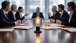 © tonstock - Glowing light bulb on a conference table symbolizing a creative business idea during a corporate team meeting.