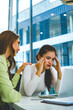 © MIND AND I - Businesswoman Comforting Stressed Colleague at Office Desk