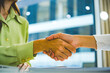 © MIND AND I - Close-Up of Businesswomen Shaking Hands Over Contract at Office Desk