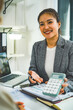 © MIND AND I - Businesswoman Showing Calculator at Desk