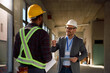 © Drazen - Happy construction site inspector talking to black worker on site.