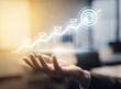 © Shahriar - A business professional holds a glowing holographic growth chart with checkmark icons leading to a target symbol, representing corporate success, strategic planning, and achievement in modern office.