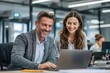 © reno - Two colleagues happily work together at a laptop in a modern office
