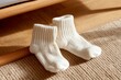© Lifia - Soft White Baby Socks on Textured Rug with Gentle Shadow and Cozy Atmosphere