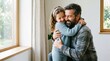© ryoga - A bearded man smiling and hugging a little girl by a sunny window on father's day.
